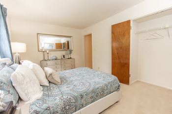 A bedroom with a white bed and a painting on the wall at The Brittany Apartments, Maryland